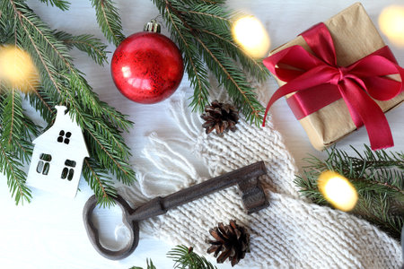big key and white house with a red ball and a gift on a table with fir branches and a scarf top view. festive decorations for winter holidaysの写真素材