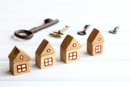 Four wooden houses on the background of blurry silhouettes of different keys. Reservation of...