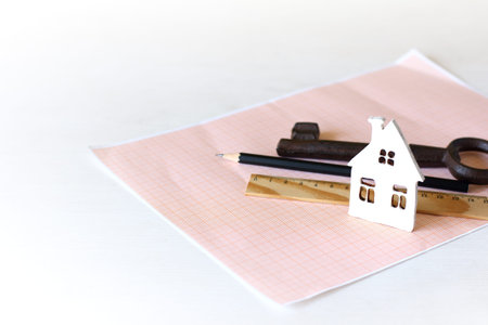 mock-up of a white house on graph paper on a background of a pencil, key and ruler. Plot Design,...