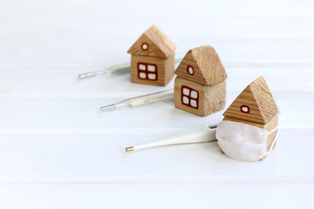 houses with thermometers, one of which is in a medical mask. symptom testing and self-isolationの写真素材