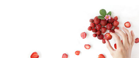 strawberries in hand laying out a heart from berries on the table top view. sweet declaration of...