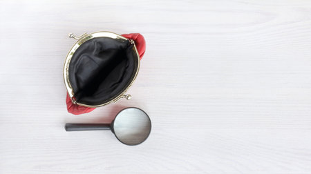 The empty wallet is open, next to a magnifying glass on a light table top view. careful check of the...