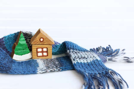 wooden house and fir trey wrapped in a knitted scarf. warm winter holidaysの写真素材