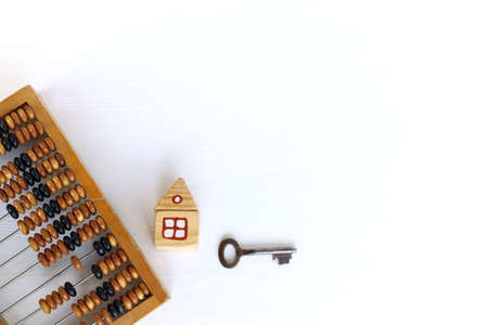 Retro computing tool and mock up of a wooden house with a metal key. traditional real estate cost calculationsの写真素材