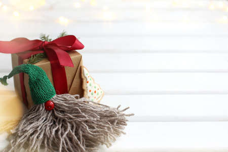 gnome in a green hat sits next to a gift with garlands in the background. surprise for Christmas and new yearの写真素材