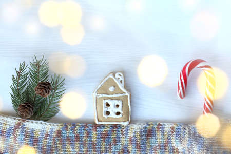 gingerbread house and striped staff candy with spruce branches and cones over a knitted scarf. home festive atmosphereの写真素材