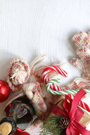 striped candy-sticks, knitted hat, scarf, mittens and a gift with a bottle of sparkling wine on the table top view. Christmas and New Year holidaysの写真素材