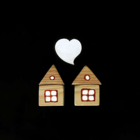 heart symbol over a pair of houses with light in the windows on a dark background. nice neighborhood relationshipの写真素材