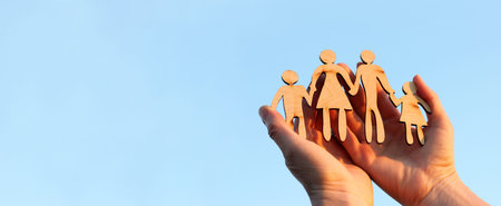 wooden silhouette of a man and a woman with two children in their arms against a background of blue...