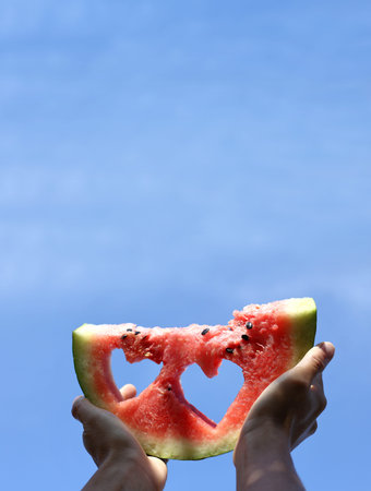 slice of watermelon with hearts against the blue sky. favorite taste of summerの写真素材