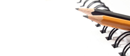pair of simple sharpened slate pencils against the background of notebook with white blank sheets. a...