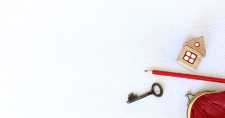 house and key with red pencil and wallet on the table with a sheet of paper top view. payment for necessary servicesの写真素材