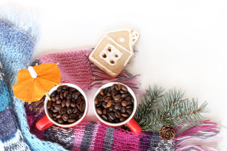 cups with roasted coffee beans, knitted scarves, spruce branch, gingerbread house top view. cozy warming homemade drinkの写真素材