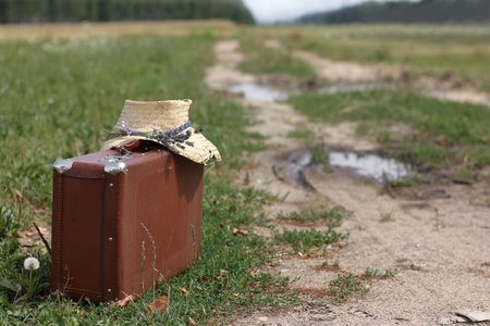 Old suitcase and hat on the road in the field. Travel conceptの写真素材