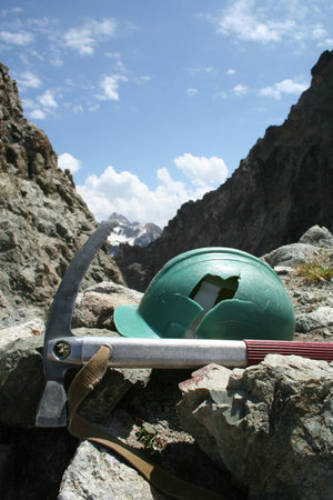 broken helmet and ice-axe with high mountains at background