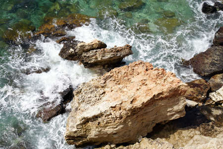 sea shore stones with foamed incoming wavesの写真素材