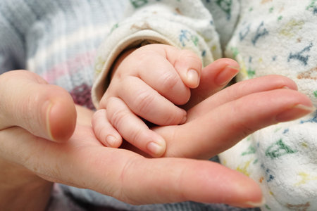 mother holding a baby`s hand in her hand