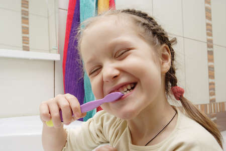 little girl screwing up one`s eyes and cleaning a teeth at the bathroom. Fun wide angleの写真素材