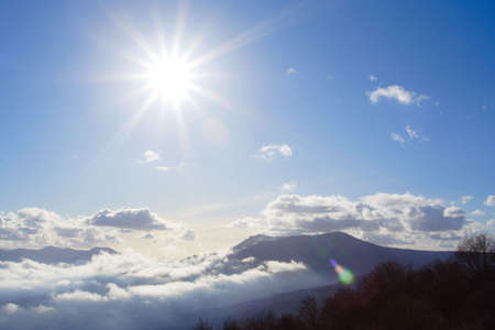 bright sun above the cloudy mountains is lighting right to the cameraの写真素材