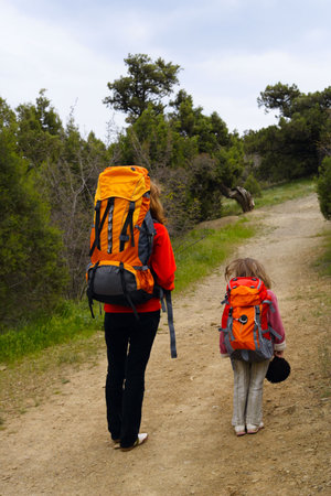 mother and daughter are hiking by the path