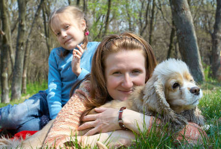 smiling mother with daughter lying on a grass holding her dogの写真素材