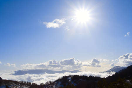 bright sun above the cloudy mountains is lighting right to the cameraの写真素材