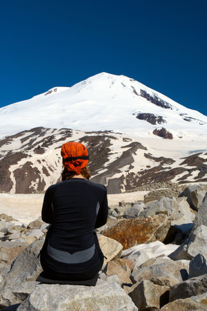 girl hiker high at the mountains looks at the ultimate aim of his trip