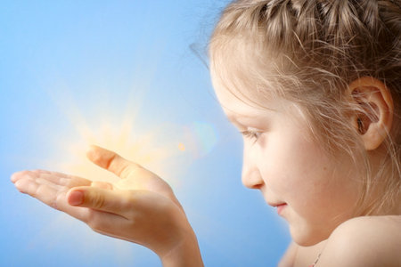 smiling child holding a sun at her hands on a blue sky backgroundの写真素材