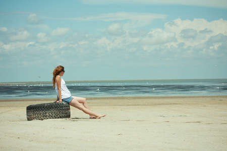 beautiful girl sitting on an empty beach.の写真素材