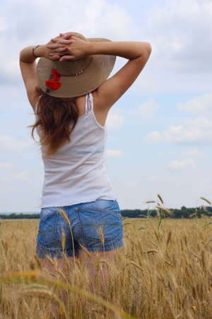 young girl joys on the wheat field with blue cloudy sky at the background.の写真素材