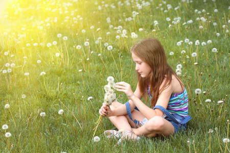 girl with dandelion and green meadow in the backgroundの写真素材