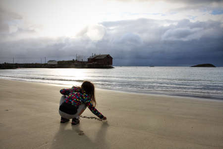 child girl sitting on a coast, Senja, norwayの写真素材