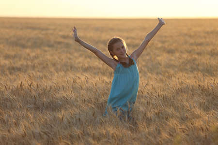 young girl joys on the wheat field  at the sunset timeの写真素材