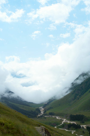 wide green valley and mountains river with clouds sky in the distance