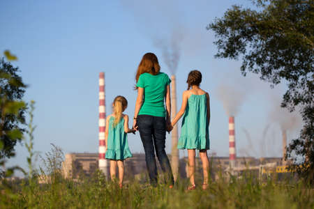 care future concept. Young mother with her kids are looking at the chimney-stalks polluting an air
の写真素材