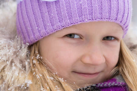 little smiling girl outdoors at the snowfall timeの写真素材