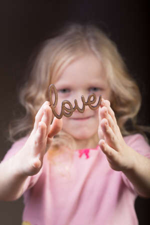 little girl holding a word Love at her handsの写真素材