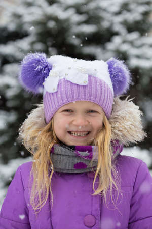 little smiling girl outdoors at the snowfall timeの写真素材