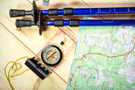 compass, map, trekking poles and backpack on a wooden backgroundの写真素材