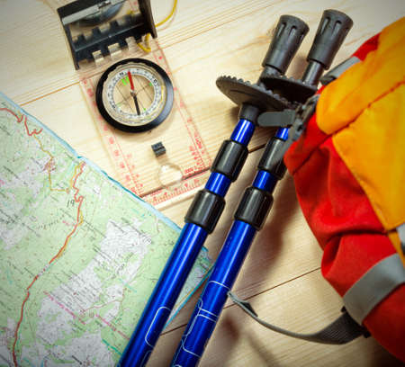 compass, map, trekking poles and backpack on a wooden backgroundの写真素材