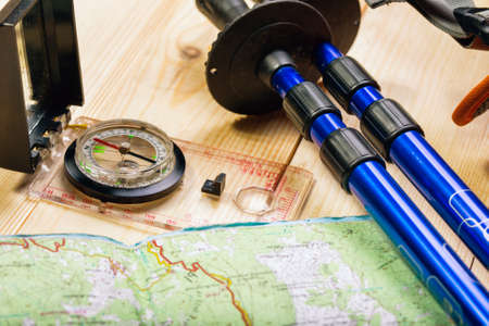 compass, map, trekking poles and backpack on a wooden backgroundの写真素材
