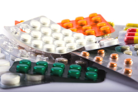 heap of multicolored pills with blisters lying on a white background