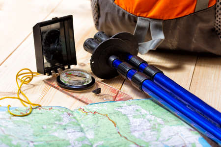 compass, map, trekking poles and backpack on a wooden backgroundの写真素材