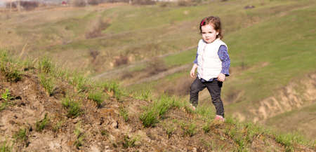 Little girl walks on a hill outdoorsの写真素材