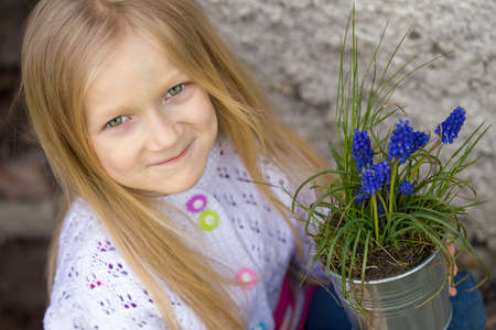 smiling girl holding flowers hyacinths  in a potの写真素材