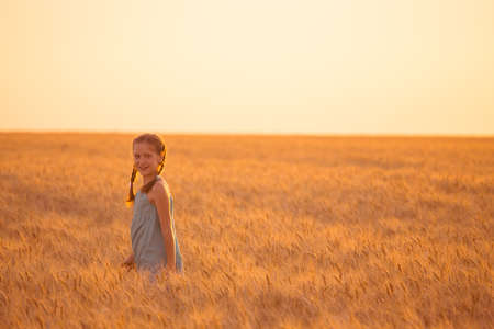 young girl joys on the wheat field at the sunset timeの写真素材