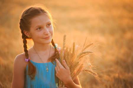 young girl joys on the wheat field at the sunset timeの写真素材