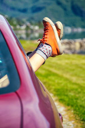 Girl legs in bright sneakers sticking out of the carの写真素材