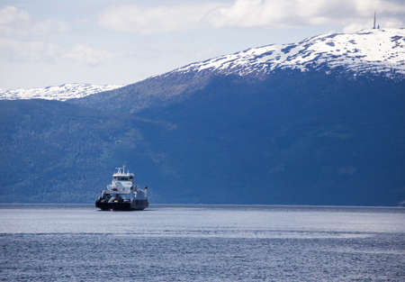 ferry crossing a norwegian fjord with mountains at the backgroundの写真素材
