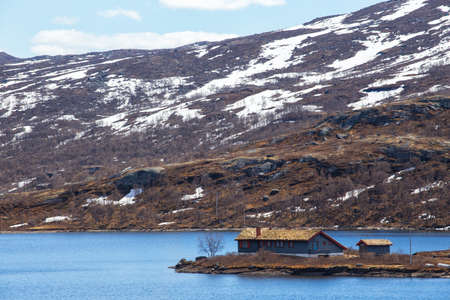 traditional norwegian wooden house to stand at the lakeside and mountains in the distance, norwayの写真素材